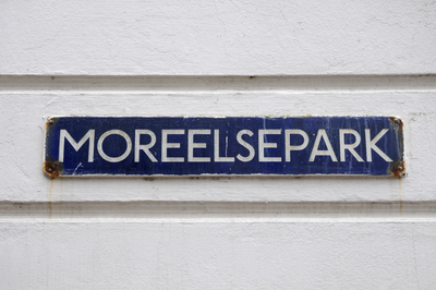 909728 Afbeelding van het oude type straatnaambord Moreelsepark op de zijgevel van het voormalige Hoofdgebouw I (HGB I, ...